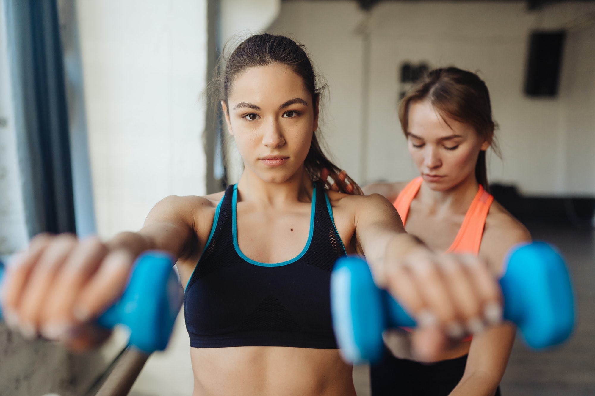 young woman personal trainer helping with workout at gym 1